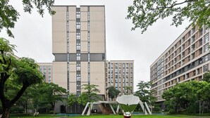A modern building with a flat roof and multiple windows, surrounded by green trees and a grassy area with a sculpture. - Baiyun International Airport Center apartments (Guang Zhou Shi)