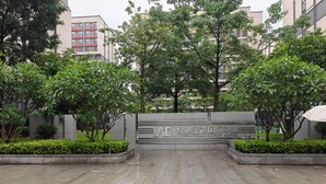 A paved entrance with a sign for the International Airport Center, surrounded by greenery and modern buildings.