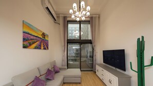 A modern living room with a sofa, TV, and artwork on the wall.