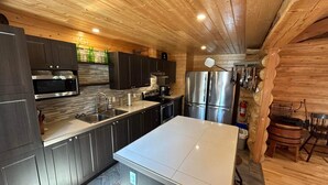 Una cocina moderna con armarios oscuros, electrodomésticos de acero inoxidable y una isla blanca.