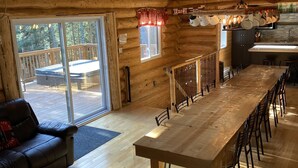 Una cabaña de madera espaciosa con una amplia mesa de comedor, un sofá y una zona de cocina.