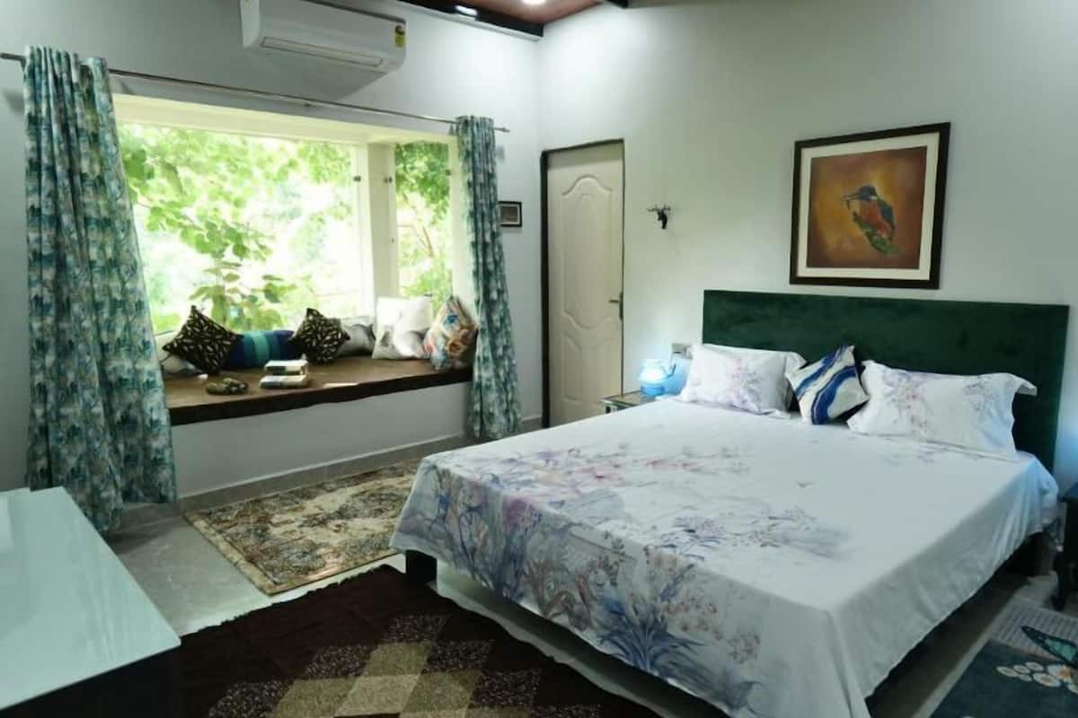 Une chambre à coucher avec un lit, une fenêtre avec des rideaux, un tableau au mur et une porte.