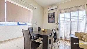 Relax in this spacious living room with a dining area, featuring a large window, dining table, and comfortable seating.