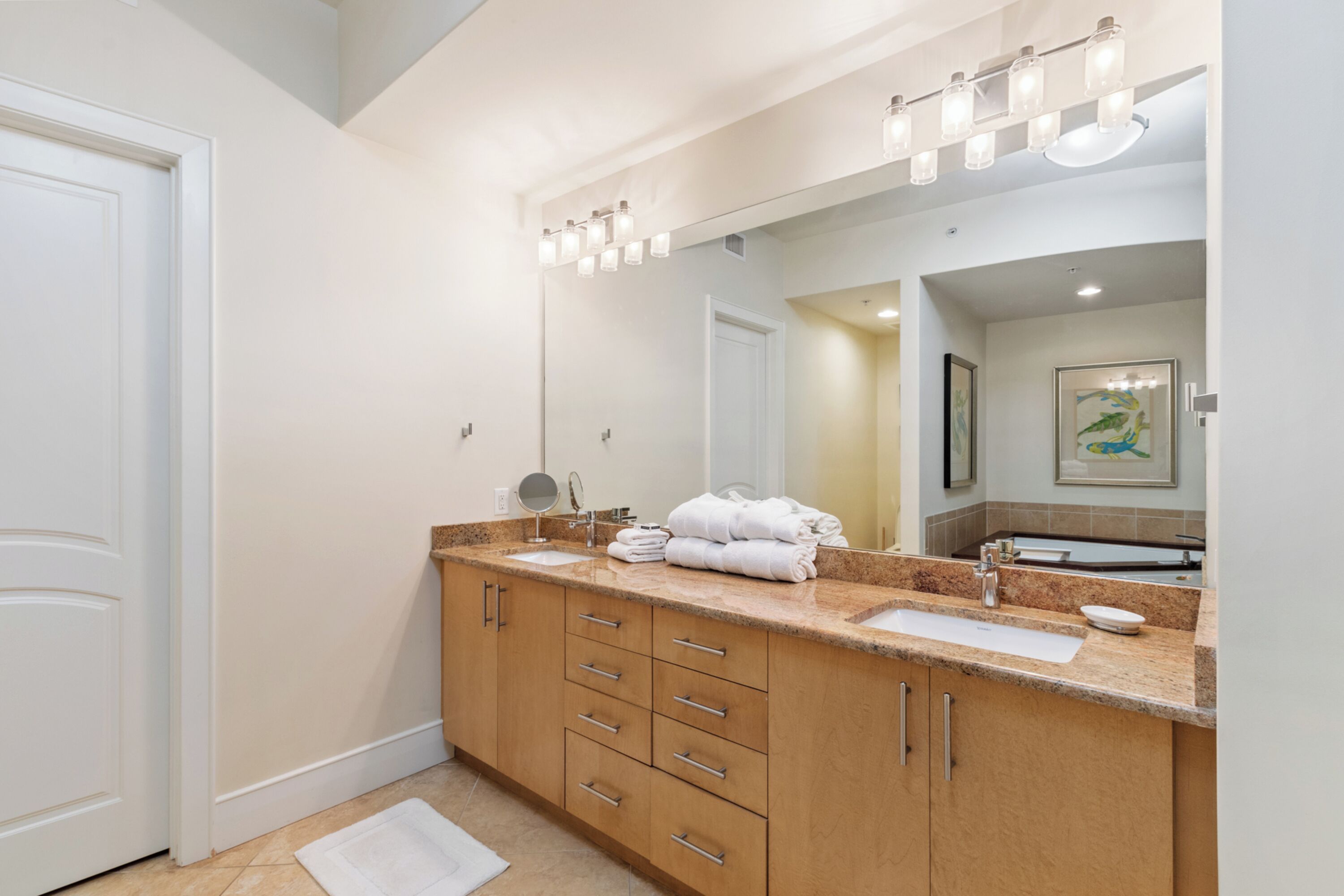 Un baño moderno con un espejo grande, dos lavamanos y un mueble de tocador con cajones.