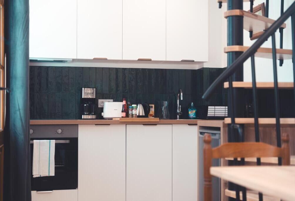 Une cuisine avec des meubles blancs, un plan de travail en bois et une machine à café.