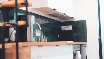 A modern kitchen with a wooden countertop, a stainless steel range hood, and a black backsplash.