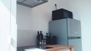 A compact kitchen with a stainless steel refrigerator, a microwave, and a wooden countertop.