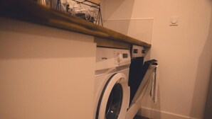 Un angolo lavanderia funzionale con lavatrice, stendibiancheria e un piccolo ripiano con diversi oggetti.