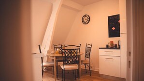 A cozy kitchen with a dining table, chairs, a clock, and a chalkboard with writing.