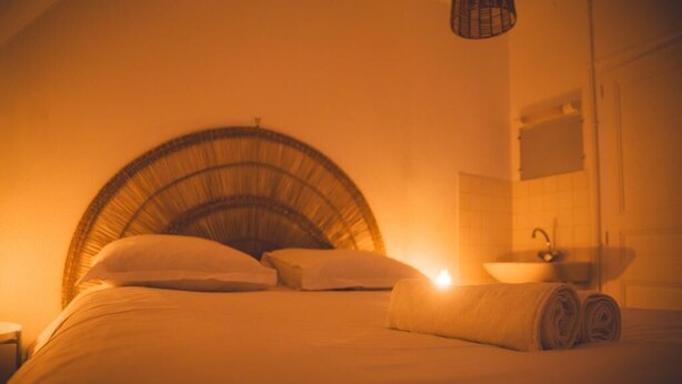 A bed with a curved headboard, a bedside table, and a rolled towel.