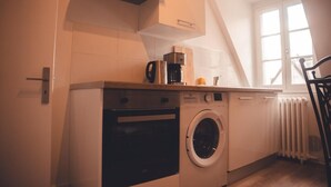 A compact kitchen with a built-in washer and dryer, a coffee maker, and a window providing natural light.