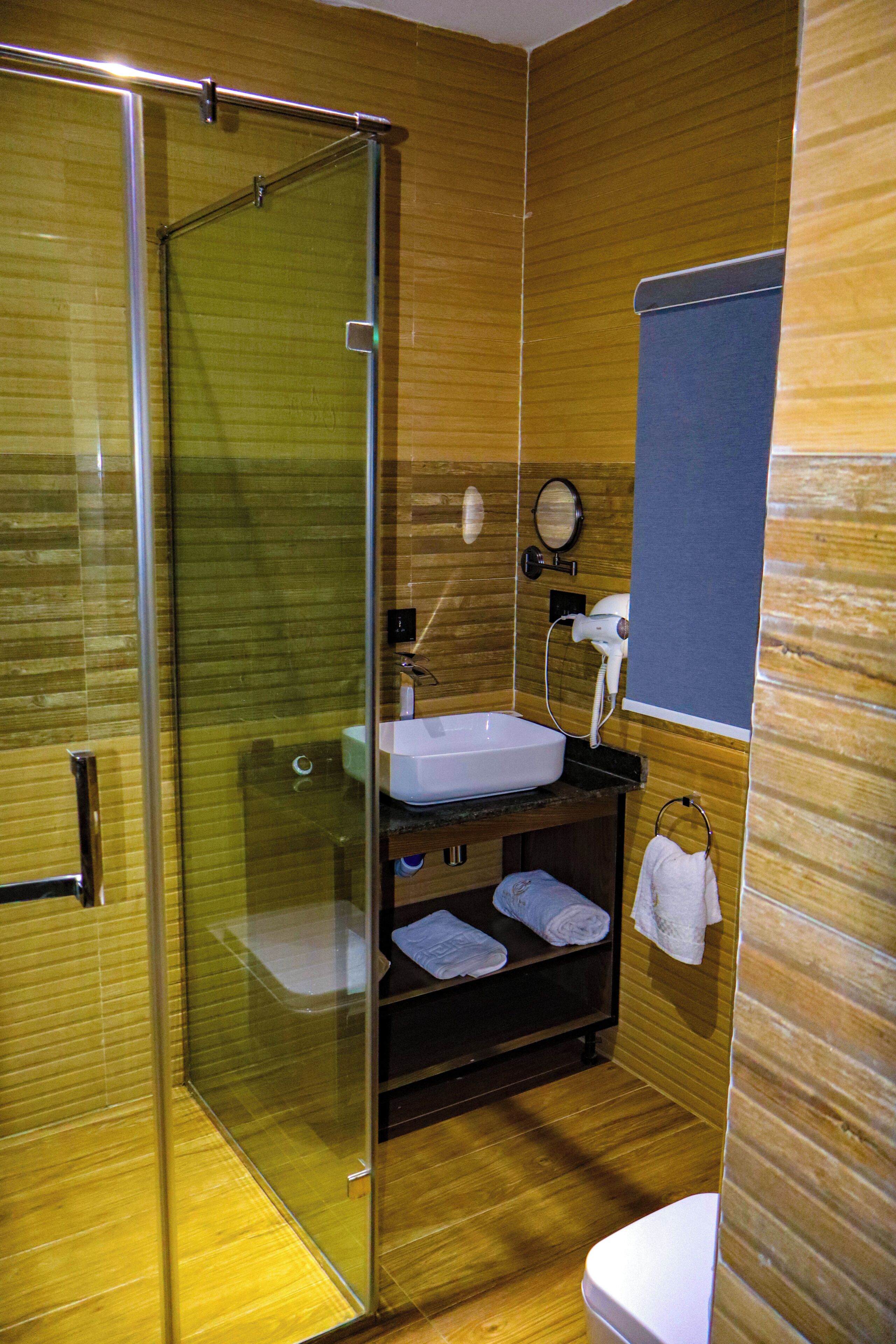 A modern bathroom with a glass shower enclosure, a sink, and a toilet.