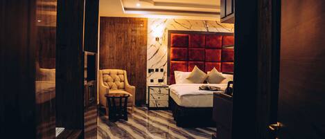 A hotel room with a marble floor, a tufted headboard, a bed with pillows, a nightstand, and a chair.