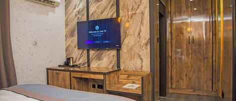 A hotel room with a bed, a TV mounted on a marble wall, a wooden cabinet, and a wardrobe.