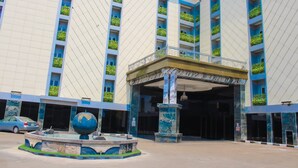 A hotel entrance with a large globe fountain, a covered entrance, and a car parked in front.