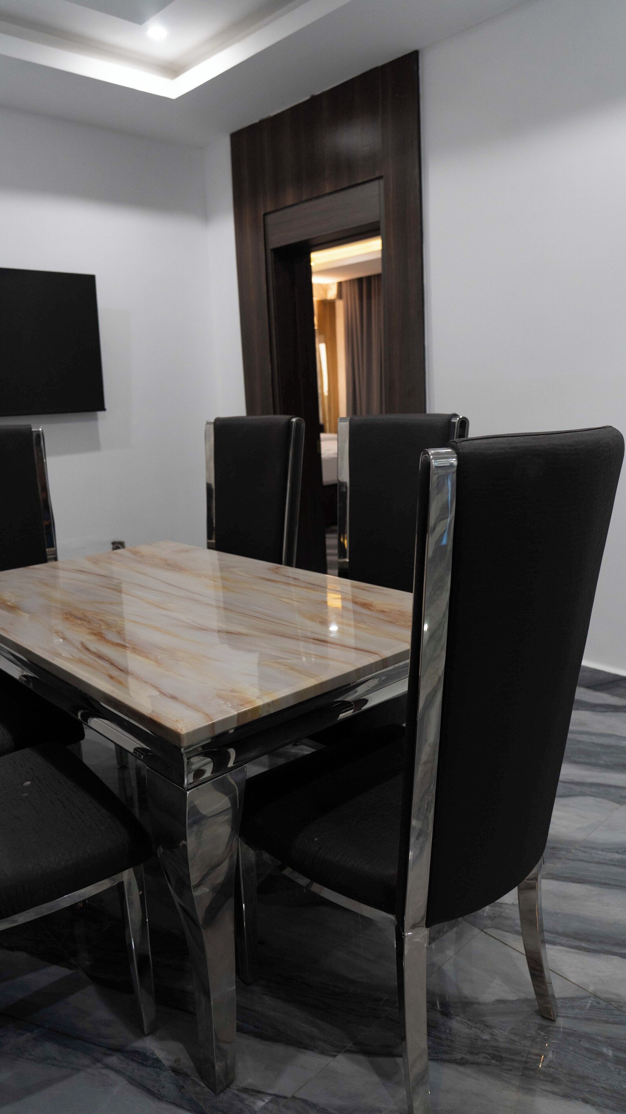 A conference room with a marble table, black chairs, and a flat-screen TV mounted on the wall.