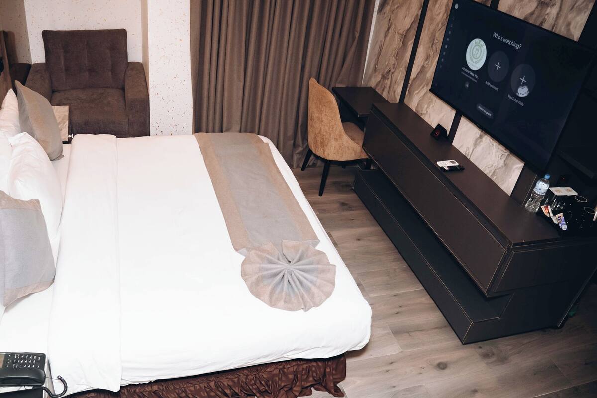 A hotel room with a bed, a TV, a desk, and a chair.