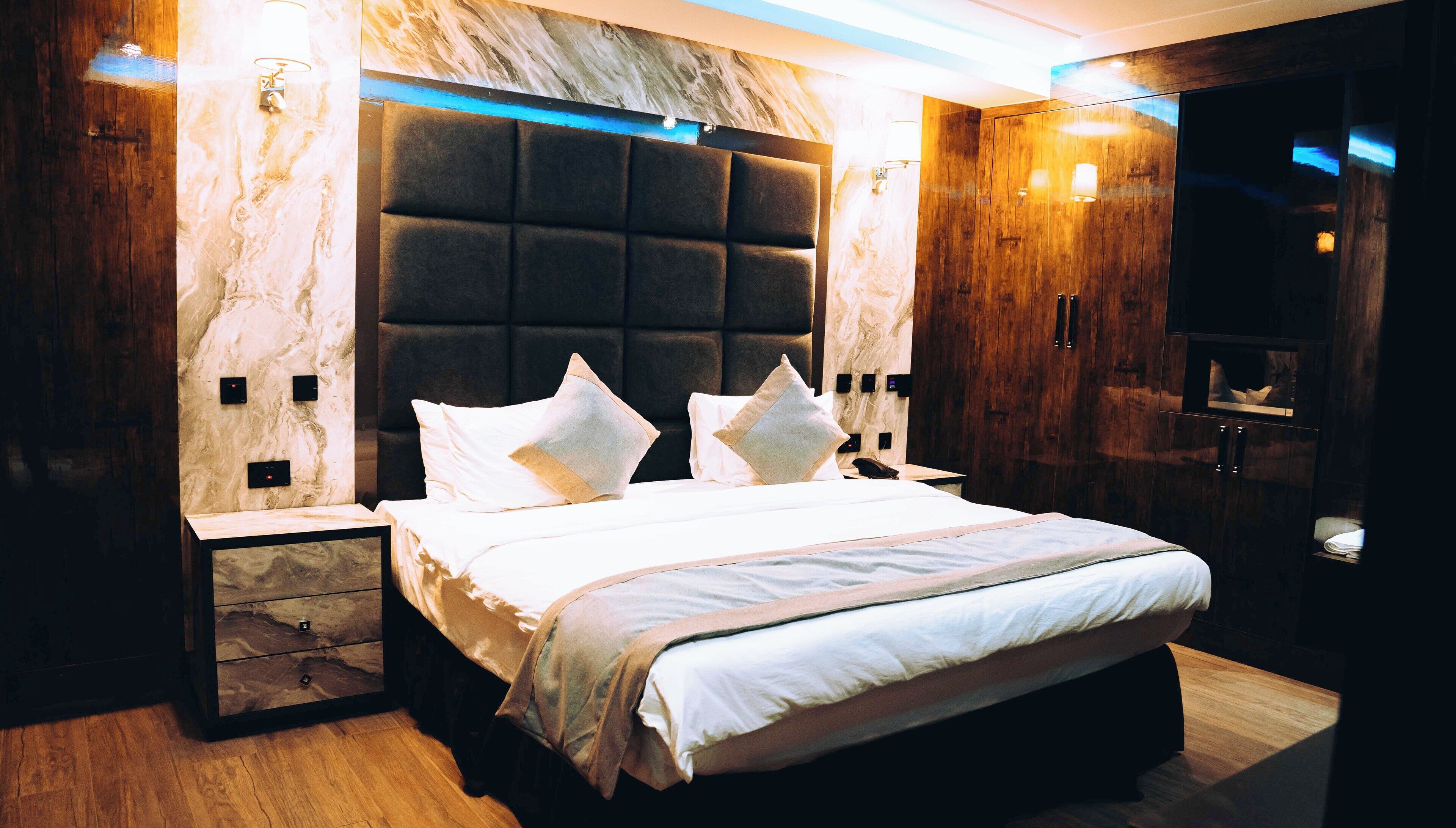 A modern bedroom with a large bed, marble wall, and wooden accents.
