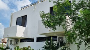 Un edificio moderno con techo plano, varias ventanas y unidades de aire acondicionado.