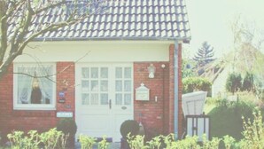 A small brick house with a white door, a window with curtains, and a mailbox. - Haus Hanne Sylt ♥ Apartment OG- Maisonette in Alt Westerland. Families welcome! (Sylt)