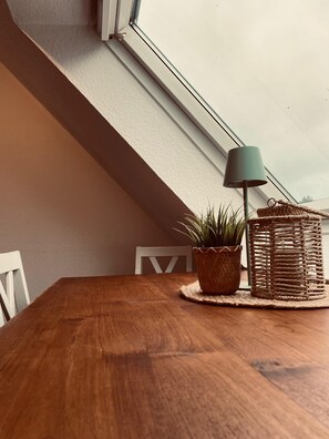 Une table de salle à manger en bois, avec un panier tressé et une plante en pot.