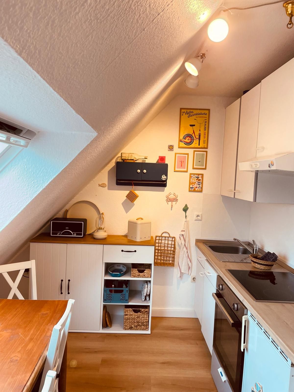 Uma cozinha compacta com armários brancos, uma mesa de jantar de madeira e um forno pequeno.