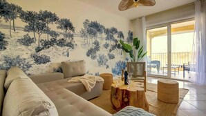 A living room with a sofa, a coffee table, and a wall mural. - Boheme Piscine Chauffee Privee, 8P - Les Cottages du Tarn (Peyrole)