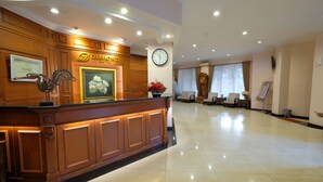 Ein Hotel-Empfangsbereich mit einem Holzbüro, einer Uhr und einem gerahmten Bild an der Wand.