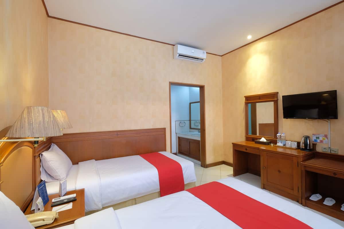 Quarto de hotel com duas camas, uma escrivaninha, uma televisão e um espelho.
