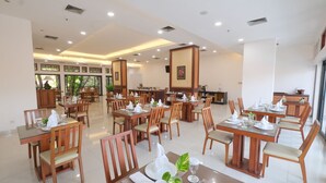 Un comedor amplio con varias mesas y sillas, bien iluminado por luces de techo, y con un diseño moderno y limpio.