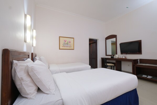 Habitación de hotel con cama, escritorio, televisor y un cuadro en la pared.
