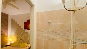 A hotel room with a bed, a bedside lamp, a bathroom with a sink and mirror, and a staircase leading to another room. - Europe station rooms (Parma)