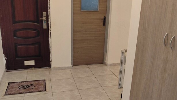 A hallway with a wooden door, a small window, and a radiator.