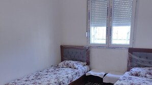 A bedroom with two wooden beds, a window with blinds, and a pink rug.