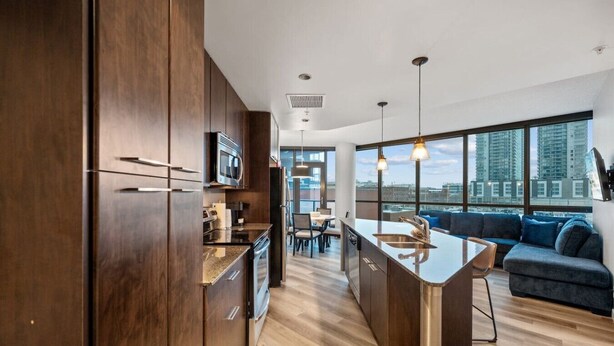 A modern kitchen with dark wood cabinets, stainless steel appliances, and a large island with a sink.