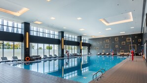 An indoor swimming pool with clear glass walls, sunlit ceiling, and modern design. - Nanjing Yangzi River Conference Center Longshan Lake Hotel (Nanjing)