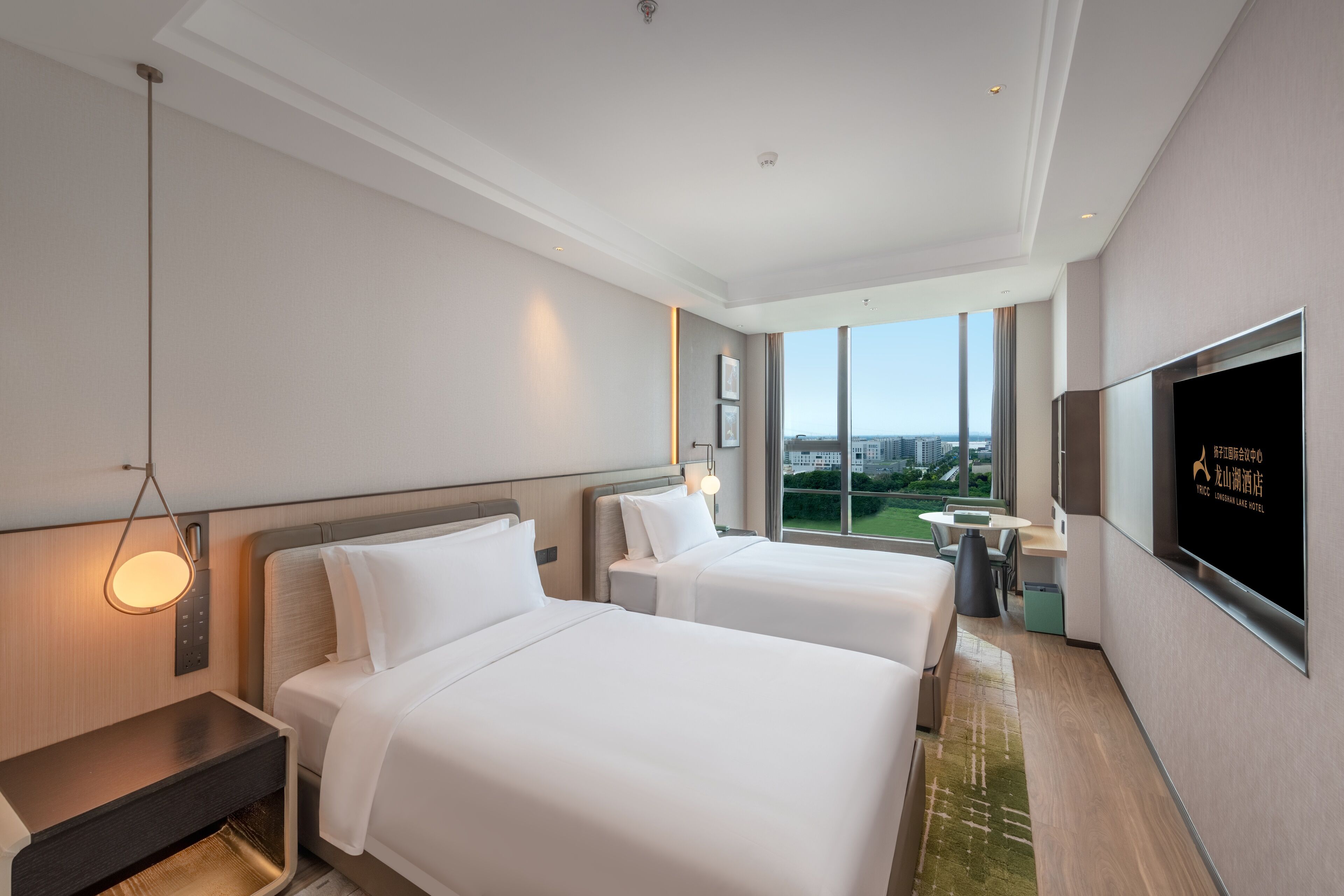 Une chambre d’hôtel avec deux lits, une télévision, un bureau et une vue sur la ville.