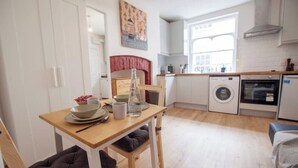 A compact kitchen with a dining area, a washing machine, and a small oven.