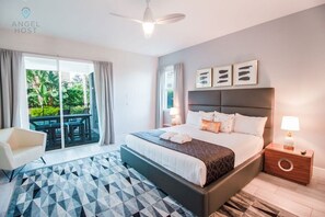A modern hotel room with a large bed, a desk, and a balcony with outdoor seating.