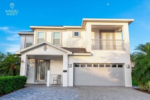 A modern two-story house with a garage, a balcony, and a well-maintained front yard. - Relaxing Family Retreat: Pool, Spa, Theater, Games (Kissimmee)