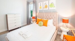 A neatly arranged bedroom with a large bed, a bedside table with a lamp, and a dresser. - Relaxing Family Retreat: Pool, Spa, Theater, Games (Kissimmee)