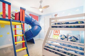 A child's room with a bunk bed, a slide, and Star Wars-themed bedding.