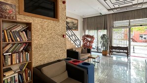 A modern lobby with a brick wall, a bookshelf, a sofa, and a staircase. - OKUR OTEL (Istanbul)