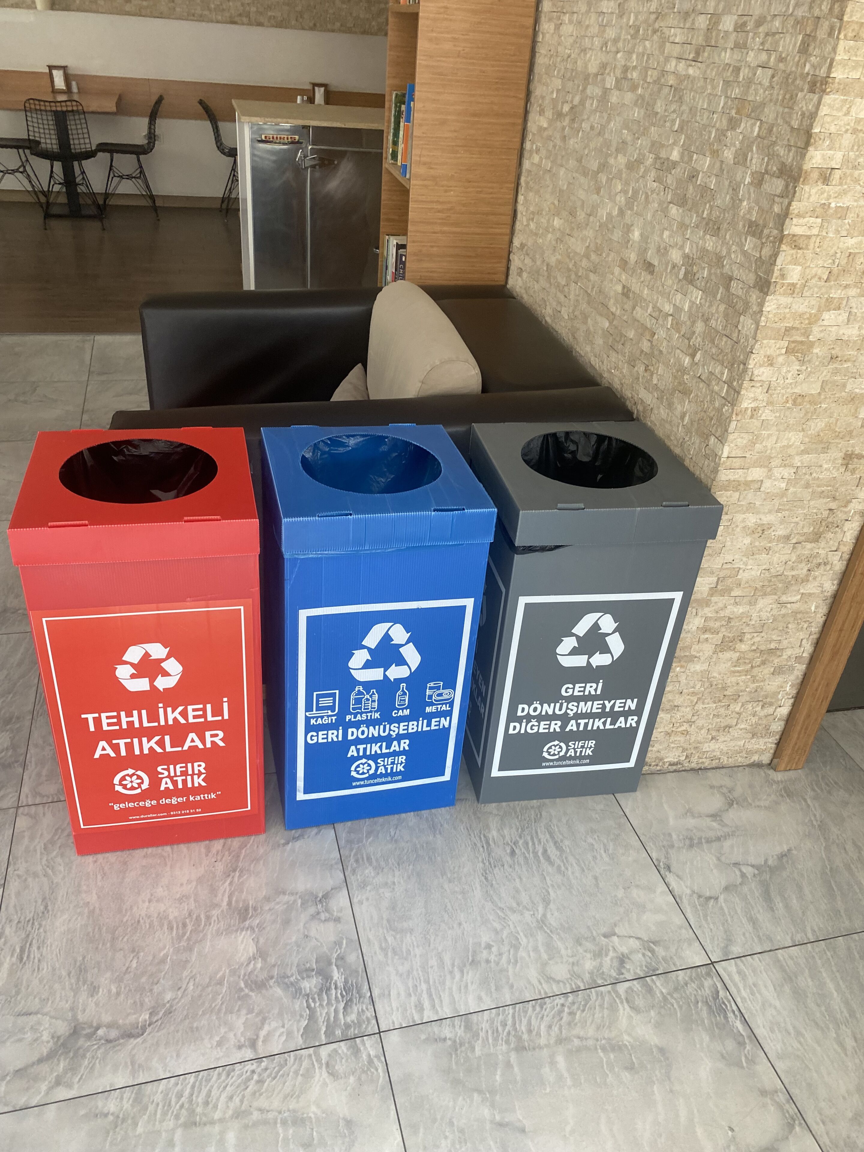 Three waste bins labeled for recycling plastic, metal, and paper.