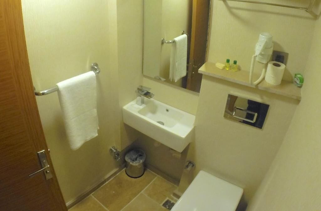 A small bathroom with a sink, mirror, and towel rack.