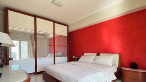 A bedroom with a bed, bedside tables, a mirror, and a wardrobe. - Beach House Roccalumera (Roccalumera)