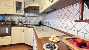 A kitchen with wooden cabinets, a sink, and a countertop with fruits. - Beach House Roccalumera (Roccalumera)