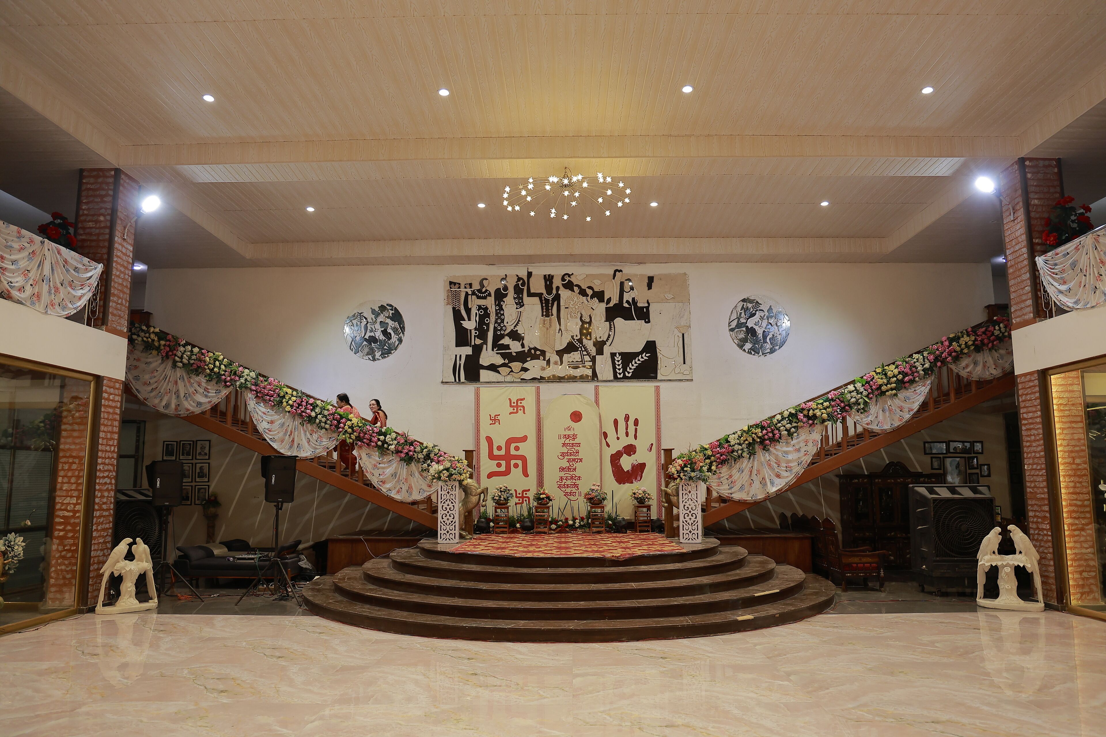 Un amplio salón con un escenario, una escalera y un gran mural en la pared.