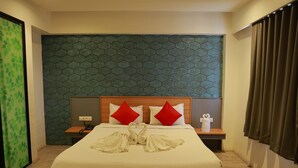 Una habitación de hotel con una cama grande, dos almohadas rojas, un cabecero de madera y una pared con diseño verde.