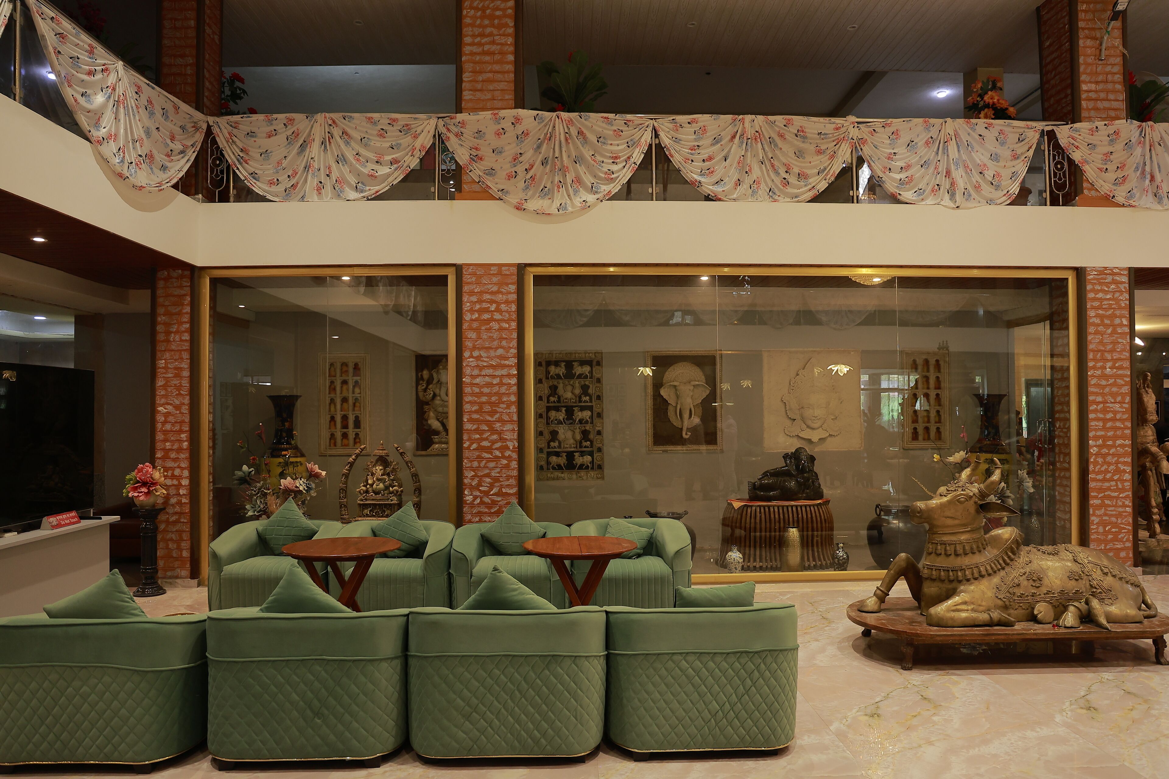 A spacious living area with green upholstered sofas, a round wooden coffee table, and a decorative animal sculpture.